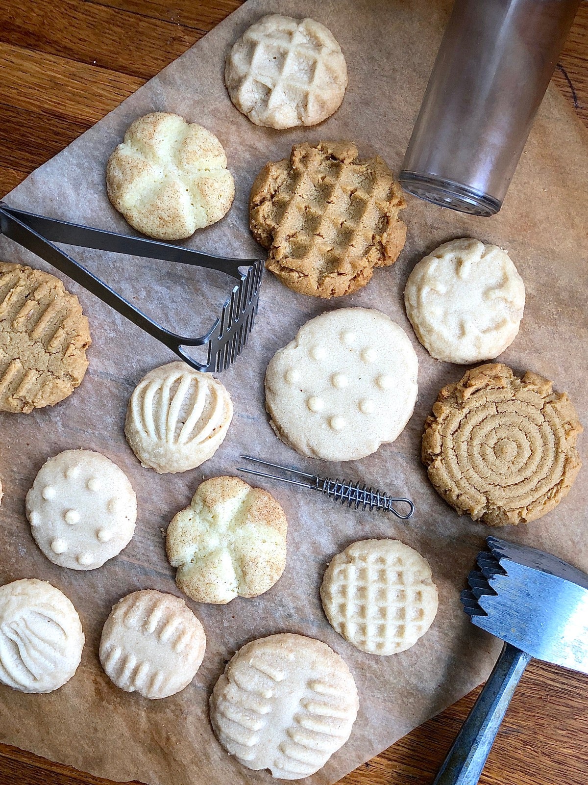 An assortment of cookies — peanut butter, shortbread, and Snickerdoodles — with imprinted tops, and the tools used to imprint.